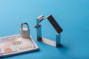 Padlock and house model on banknotes illustrating property protection and financial security information.