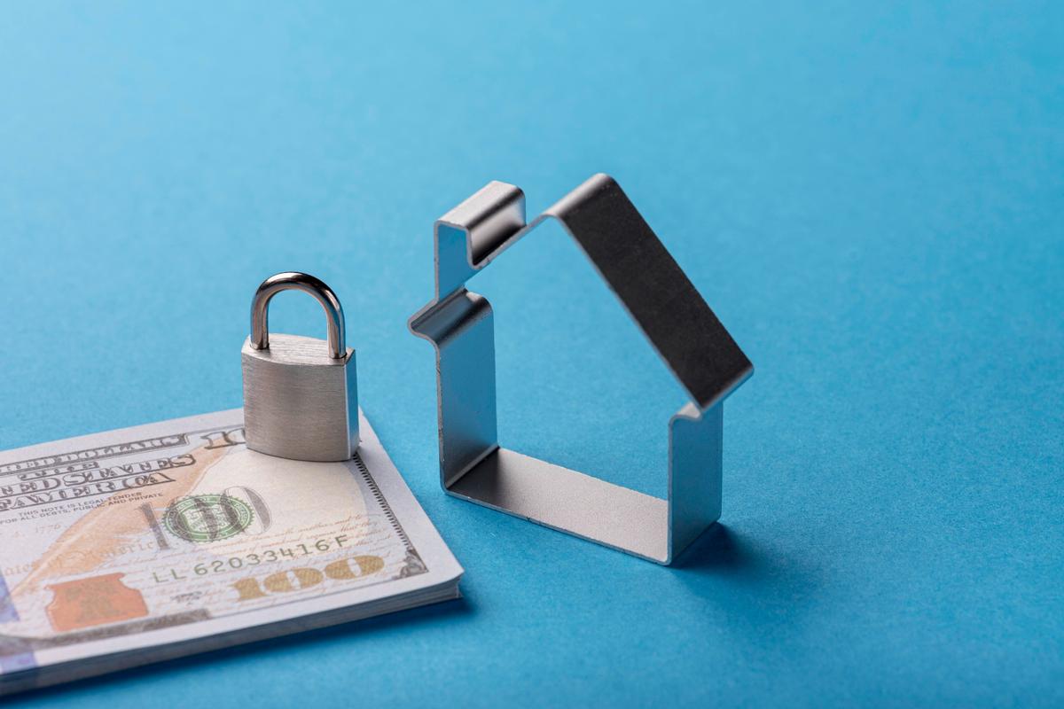 Padlock and house model on banknotes illustrating property protection and financial security information.