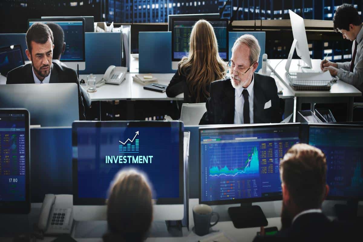 Investment professionals monitoring market trends and charts, analyzing real-time investment information on screens.