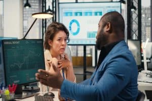 Business colleagues discussing financial information while analyzing charts and reports in a modern office.
